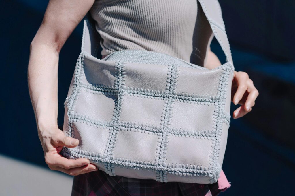 Stylish gray quilted bag held by a woman in casual attire outdoors in Krasnoyarsk.