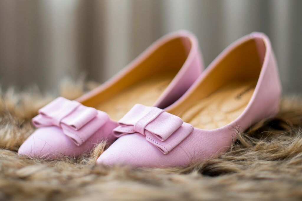Elegant pink leather flats with bow detail on furry background, perfect for a chic footwear collection.