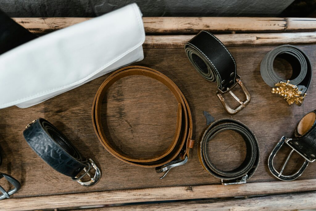 Top view of rolled leather belts arranged on a rustic wooden surface.